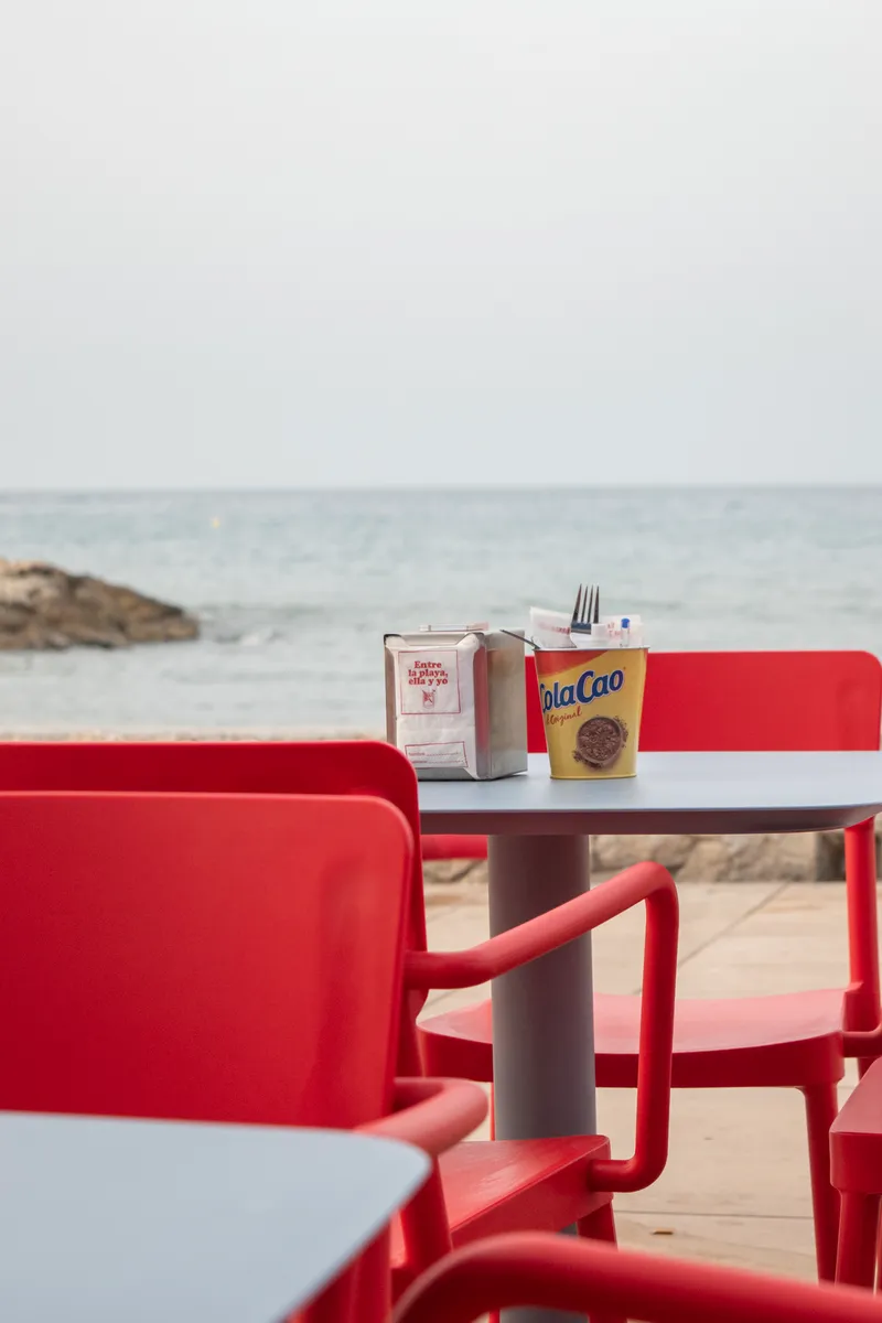 A table with red chairs facing the sea on the FOMO Playa beach bar terrace in Pedregalejo